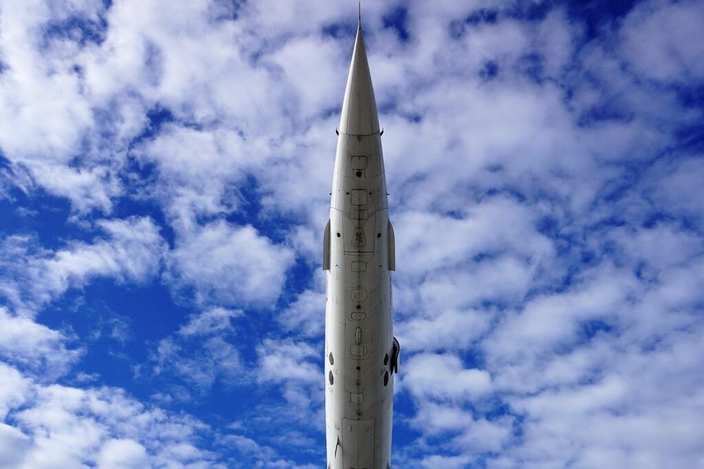 Underside view of the Concorde pointing skyward against a cloudy blue sky.